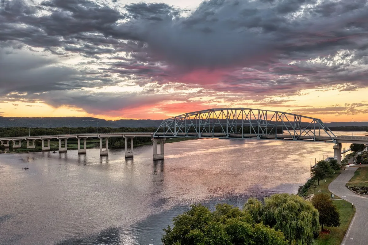 Sunset over a steel truss bridge spanning the Mississippi River.