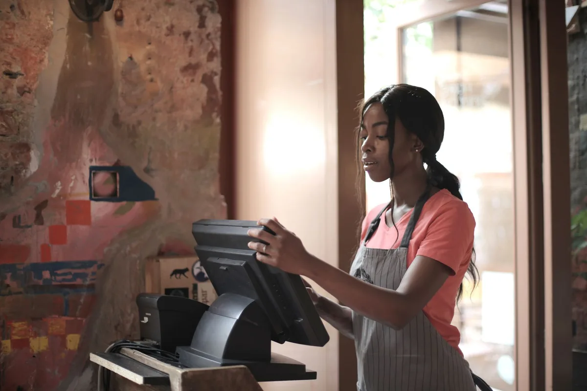 A retail cashier standing at a checkout register in a store.