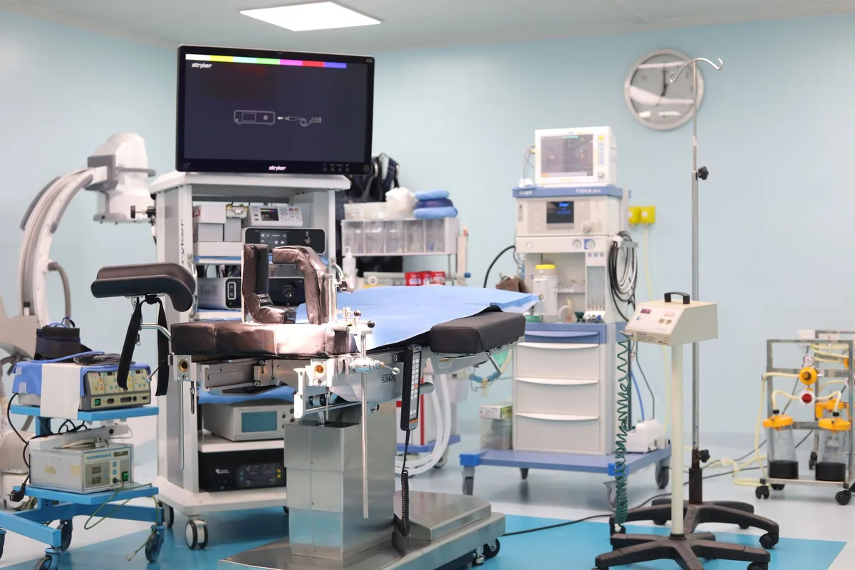An empty hospital operating room with a fluoroscopy C-arm beside the table.