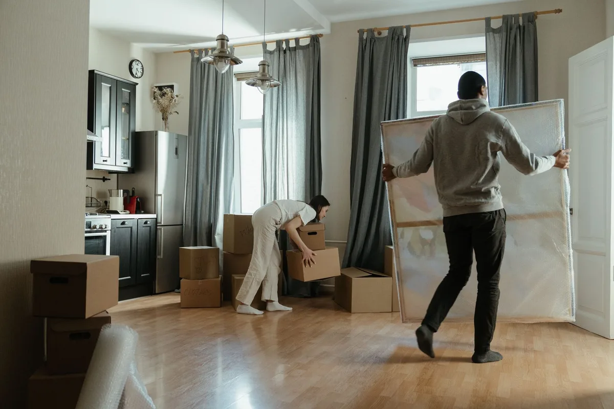 A couple unpacking cardboard moving boxes in a new apartment.