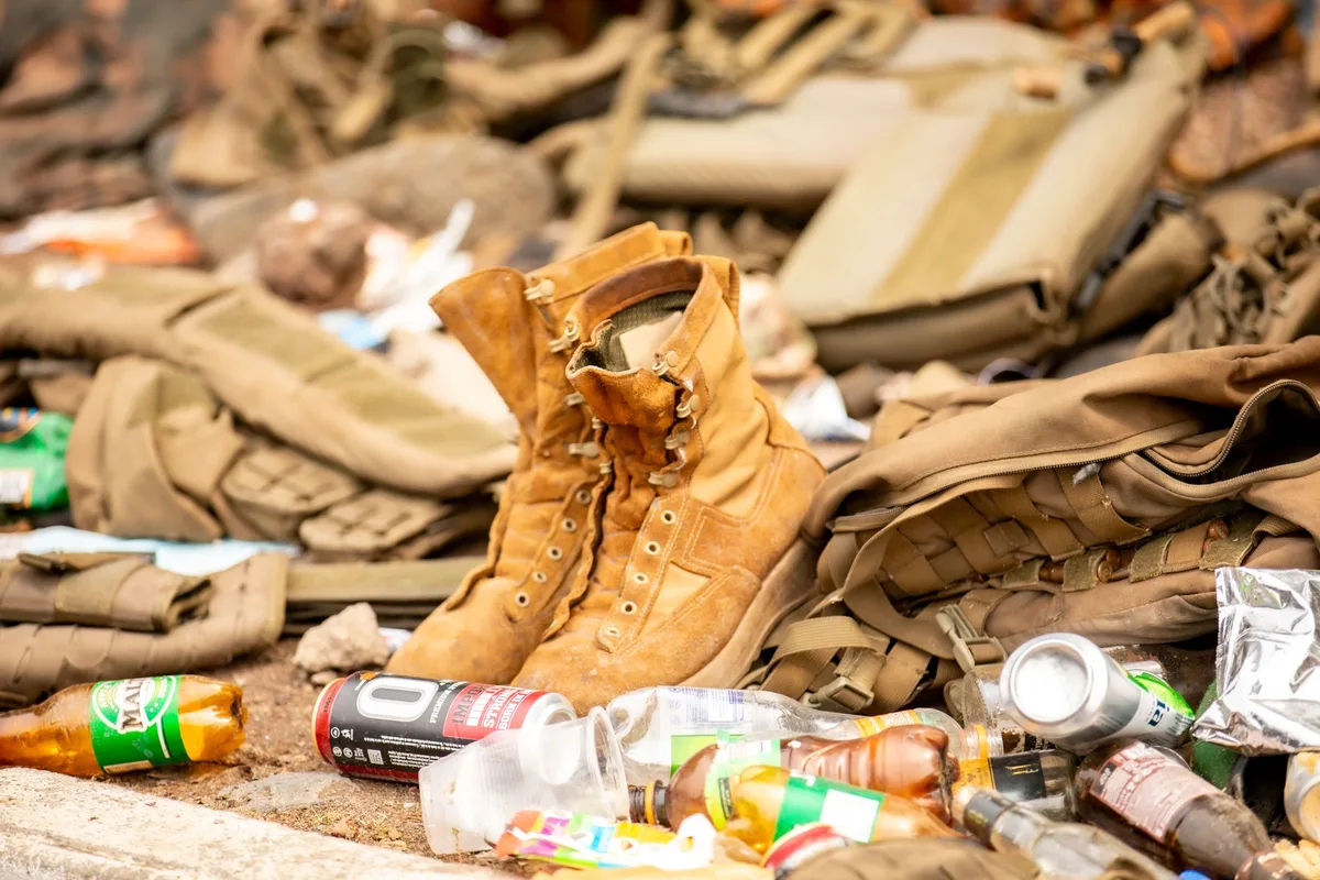 Worn military boots and field gear set down on the ground.