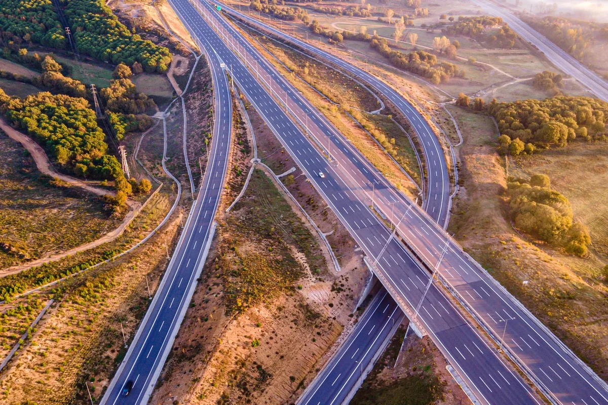 Aerial view of a highway interchange where two roads divide through open countryside.