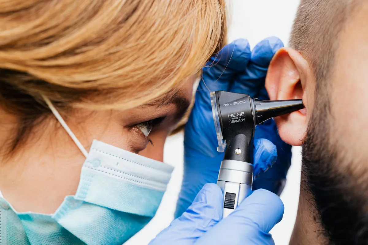 A clinician examining a patient's ear with an otoscope.