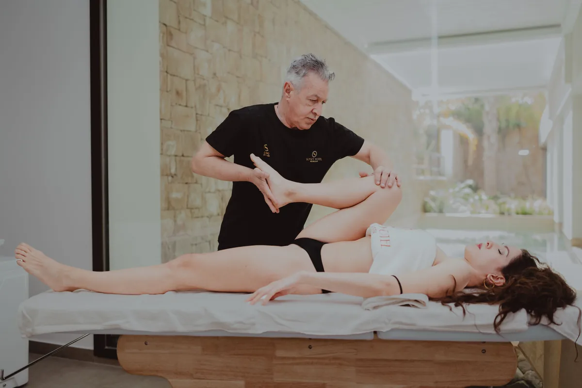 A clinician bending a patient's hip and knee on an exam table to test hip motion.